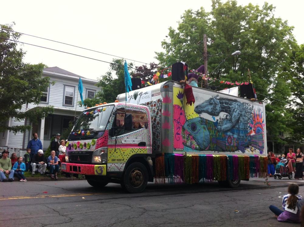 Decorated yoga truck with woman demonstrating yoga on the top; Ithaca Festival Parade, 2014